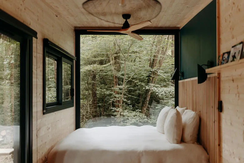 Lit d’une tiny house ouvert sur la forêt