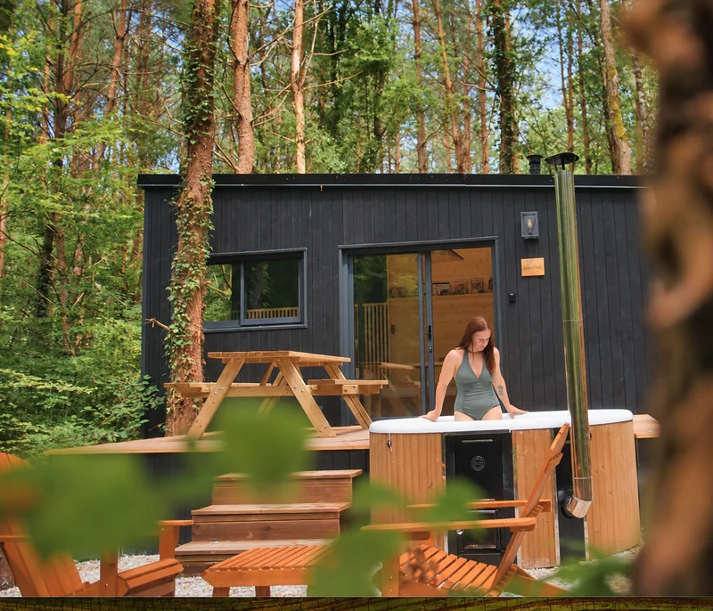 Une personne dans le bain nordique devant la tiny house Diadème, parmi les arbres